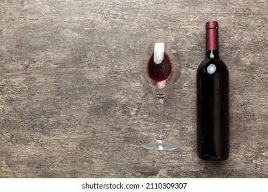 Glass Of Red Wine And A Bottle On Colored Table. Flat Lay, Top View Wth Copy Space.