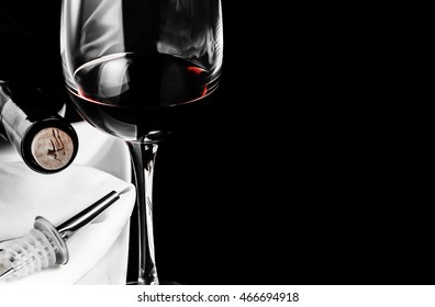 A Glass Of Red Wine, A Bottle And Tube With Dispenser On Black Background