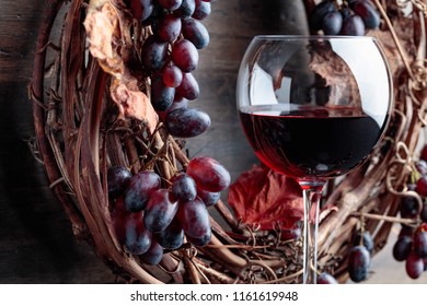 Glass of red wine with grapes and dried vine leaves.  - Powered by Shutterstock