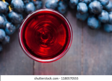glass of red wine and grapes on black wooden table background - Shutterstock ID 1180570555