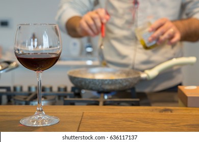 Glass Of The Red Wine In A Kitchen With Man Preparing Food