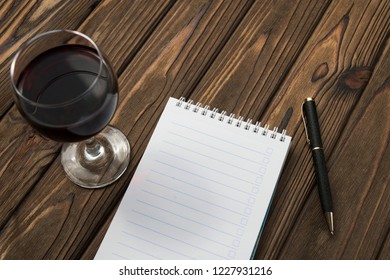 glass of red wine, Notepad, ballpoint pen on wooden table background. date, romance. - Powered by Shutterstock