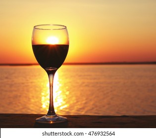 Glass Of Red Wine On Sunset Background