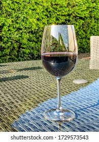 Glass Of Red Wine On The Glass Table Top Of Garden Furniture, No People, Copy Space.