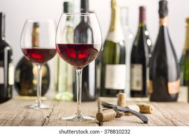 Glass Of Red Wine On Wooden Table Near Corkscrew And Bottle