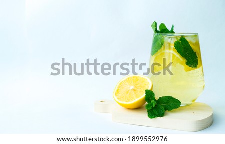 A glass of refreshing lemonade and half a lemon lie next to the glass