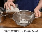 A glass of rice placed in a colander, washing and rinsing the rice to remove excess starch