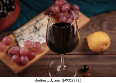 Glass of rich red wine served with cheese plate and fruits on dark wooden background. Appetizers table with wine glasses, rustic style table setting in winery - Powered by Shutterstock