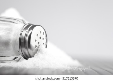стеклянная соль шейкер на сером столе и белом фоне для текста