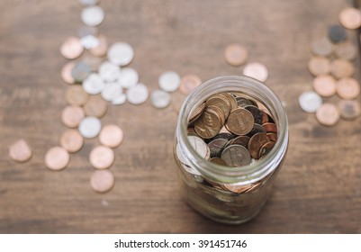 Glass Savings Jar Filled With Coins Isolated On Wooden Table.