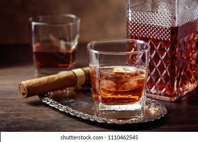 Glass Of Scotch Whiskey With Natural Ice And Cigar On Old Wooden Table.