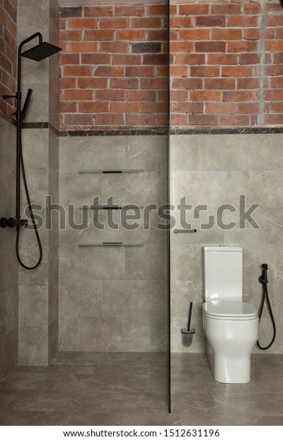 Glass\
screen dividing small bathroom into zone with traditional black\
twin shower and area with white coupled\
toilet