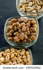 glass serving bowls with raw hazelnuts peanuts and pistachio on black slate healthy life concept