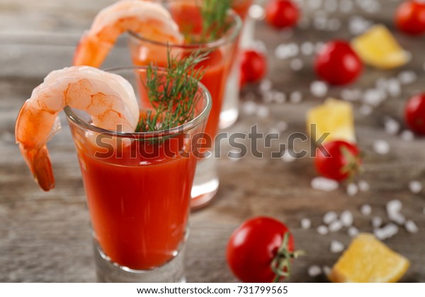 Glass with shrimp cocktail and tomato sauce on\
table, closeup