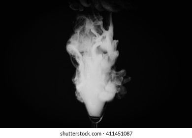 A glass with a smoke on a black background