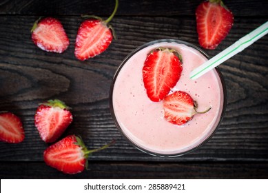 Glass Of Smoothie With Strawberries And A Banana With A Straw.