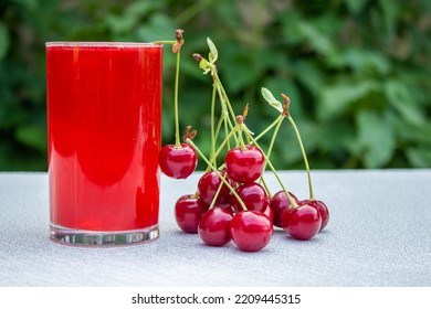 A Glass Of Sour Cherry Juice On Wooden Table With Cherry Fruits.