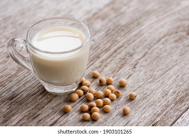 Glass of soy milk with soybeans  isolated on wooden table background.