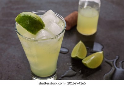 A Glass Of Sparkling Bergamot Juice With Ice And A Slice Of Lime On A Slightly Wet Black Marble Background.