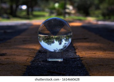 A Glass Sphere In The Center Of Road Lines That Turns The Contents Behind The Sphere Upside Down.