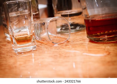 Glass, spilled whiskey and empty bottles on the bar. Abuse of alcohol hangover. Alcoholism concept. Drunk driver concept