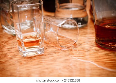 Glass, Spilled Whiskey And Empty Bottles On The Bar. Abuse Of Alcohol Hangover. Alcoholism Concept. Drunk Driver Concept