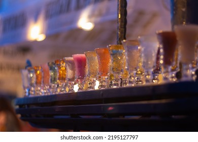 Glass Stacks Are Filled With Different Drinks As An Advertisement In A Drinking Establishment, A Bar On The Street.