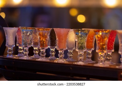 Glass Stacks Are Filled With Different Drinks As An Advertisement In A Drinking Establishment, A Bar On The Street.