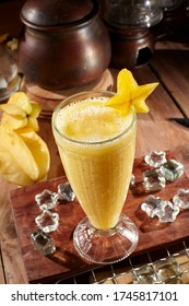 A Glass Of Starfruit Juice, Served On A Wooden Table With Ice Cubes And Star Fruit, Set Against A Ceramic Container. Isolated 
Isolated On Healthy And Nutritious Drink.