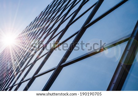 Glass and steel - mirrored facade of modern office building with sunbeams glare reflection