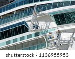 Glass and steel structure of a large cruise ship. In the picture, crewmen at work on the ship