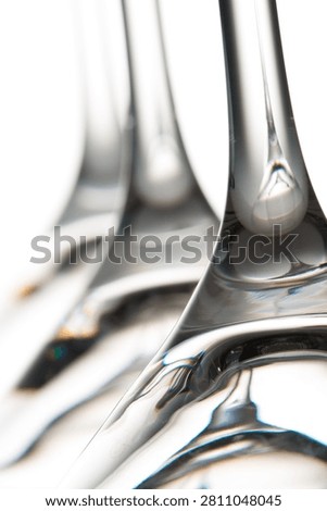 Glass stemware abstractly reflecting light and creating visual distortion on a white background