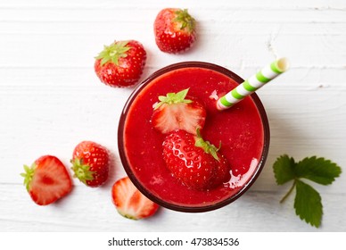 Glass Of Strawberry Smoothie On White Wooden Background From Top View