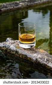 Glass of strong scotch single malt whisky served on old stone reservoir for water from mountain spring, Scotland - Shutterstock ID 2013433022