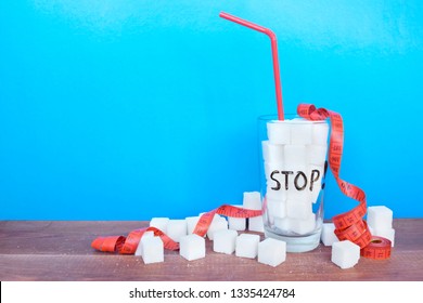 Glass With Sugar Cubes And Written Word Stop On The Blue Background. 