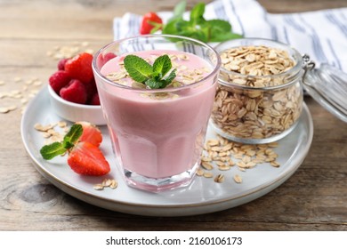 Glass of tasty berry smoothie with oatmeal on wooden table
