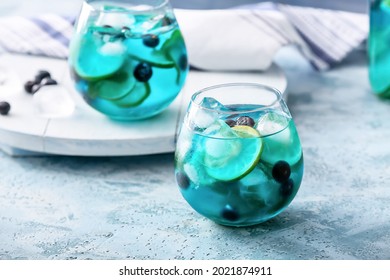 Glass of tasty blue mojito cocktail on color background