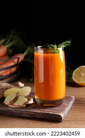 Glass Of Tasty Carrot Juice And Ingredients On Wooden Table Against Black Background