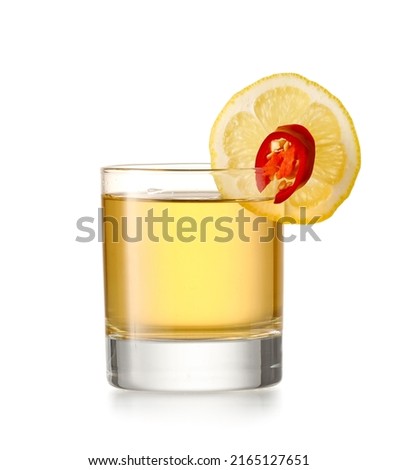 Glass of tasty mexican tequila with lemon on white background
