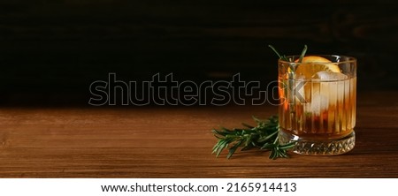 Glass of tasty Old Fashioned cocktail on table against dark background with space for text