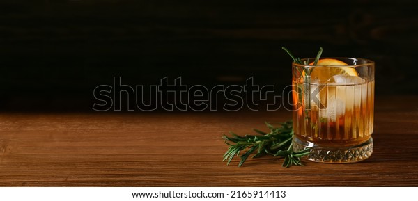 Glass of tasty Old Fashioned cocktail\
on table against dark background with space for\
text