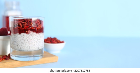 Glass of tasty pudding with goji berries and chia seeds on light blue background with space for text - Powered by Shutterstock