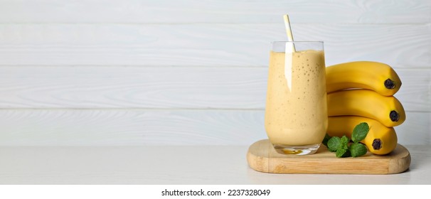 Glass of tasty smoothie, mint and fresh bananas on white wooden table, space for text. Banner design - Powered by Shutterstock