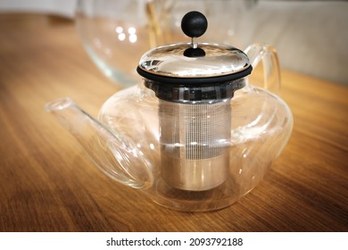 Glass Teapot with Removable Infuser, Stovetop Safe Tea Kettle, Blooming and Loose Leaf Tea Maker Set. Glass teapot on a wooden table. Transparent teapot with metal strainer for loose tea.