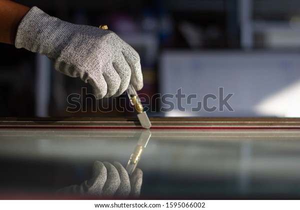 The glass technician is cutting the glass\
according to the customer\'s\
order.