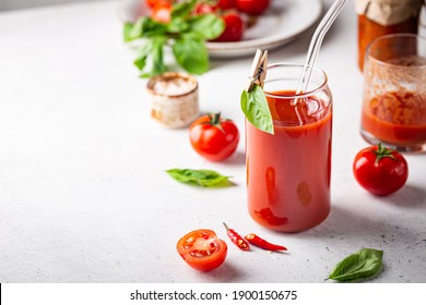 Glass of tomato juice with basil and fresh tomatoes on white background