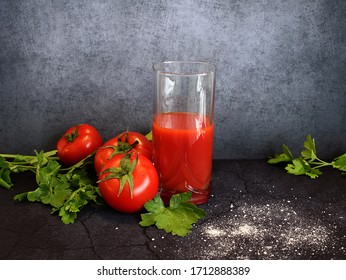 glass glass of tomato juice with fresh bright tomatoes, green parsley and salt grains on a dark background