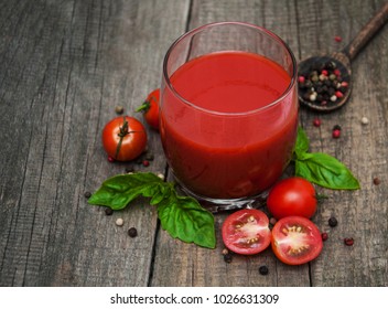 Glass with tomato juice and fresh tomatoes on a table
