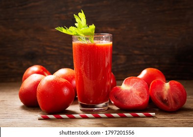 glass of tomato juice with fresh tomatoes on a wooden table