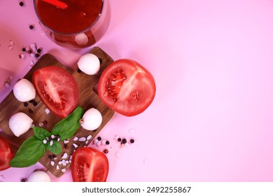 A glass of tomato juice with fresh tomatoes, mozzarella and basil on a pink background. Peppercorns and coarse salt on the surface. Healthy eating - Powered by Shutterstock